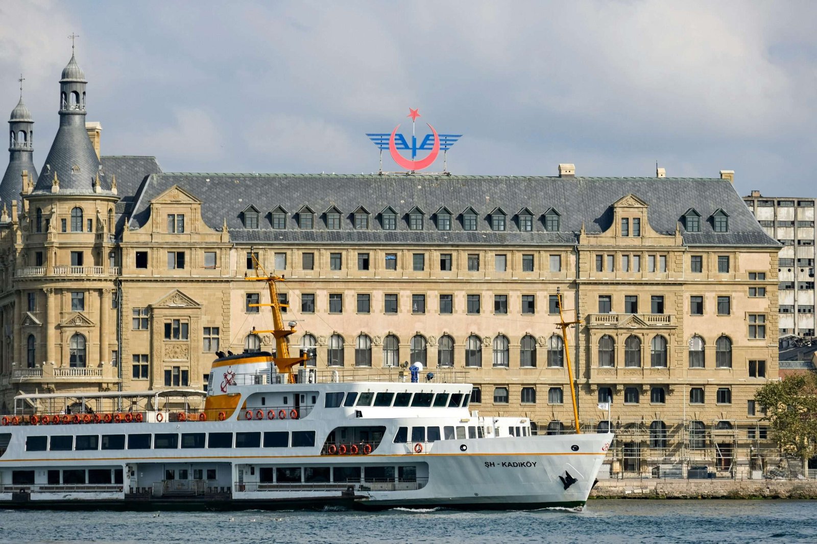 Historic ferry sails past the iconic Haydarpaşa Terminal in Istanbul, Turkey.