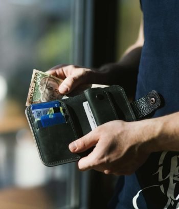 Close-up of a man holding a wallet with cash and credit cards, indoors.