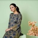 Young woman in floral embroidered dress posing with flowers indoors.