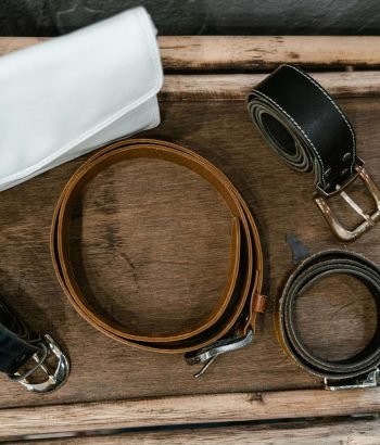 Top view of rolled leather belts arranged on a rustic wooden surface.