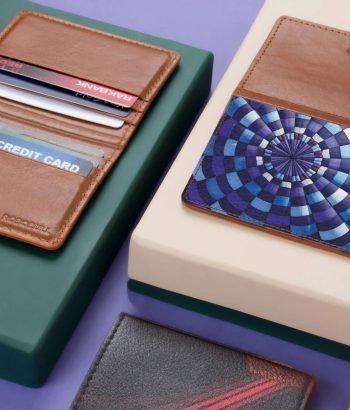 Close-up of assorted leather wallets and cardholders on a modern violet and green background.